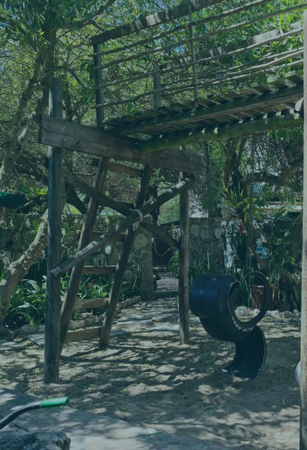 Outdoor wooden play structure with climbing and swing area at The Plot.
