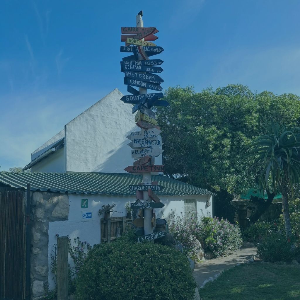 Rustic wooden signpost with travel directions at The Plot in Jacobsbaai